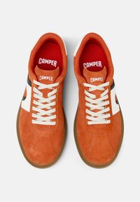 Orange Wildledersneaker mit weißen Akzenten, Schnürdesign und einer braunen Gummisohle. Merkmale sind eine auffällige Markierung auf der Zunge und der Innensohle.