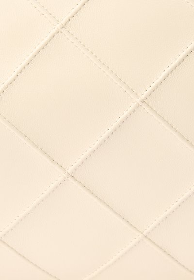 Υφή κρεμ δερματίνης με ραφές διαγώνιες που σχηματίζουν διαμάντια.