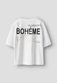 T-shirt blanc ample à manches courtes, avec un texte noir et rose clair "BOHÉME Art Club MOMENTS EMBRACE IMPERFECTION" sur le devant.