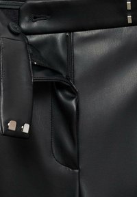 Zwarzen leren broek met een ritssluiting, knoopsluiting en metalen accenten. Heeft een slanke textuur en een op maat gemaakt ontwerp.