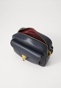 Borsa a tracolla in pelle blu navy con texture liscia, hardware dorato, zip superiore e interno bordeaux. Patta anteriore con chiusura a scatto.