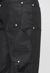 Pantalon cargo noir avec plusieurs poches, détails en métal argenté et texture lisse, au design ajusté.