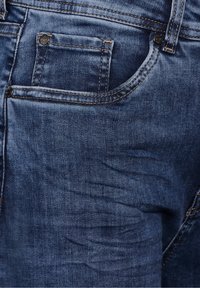 Jeans de denim azul oscuro con una textura suave, que presentan un pequeño bolsillo frontal, costuras en contraste y un diseño clásico de cinco bolsillos.