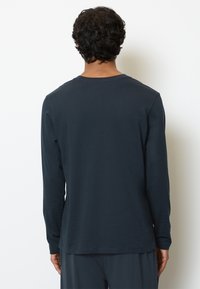 Camicia a maniche lunghe in cotone blu navy scuro, design a girocollo, texture liscia, presenta una vestibilità comoda e dettagli di cucitura sottili.