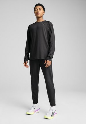 Zwart sportshirt met lange mouwen, gecombineerd met bijpassende zwarte broek. Lichtgewicht materiaal, smal ontwerp, met een klein logo op de borst.