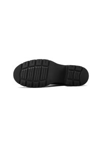 Suela de zapato de goma negra con un patrón texturizado que presenta surcos y protuberancias para mayor tracción. Diseño de punta redondeada y tacón grueso.