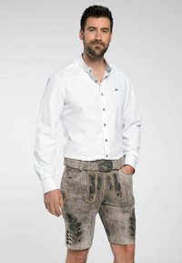 Witte langemouwshirt met een button-down kraag en grijze accenten, gecombineerd met grijze leren shorts met reliëf bloemenpatronen en decoratieve knopen.