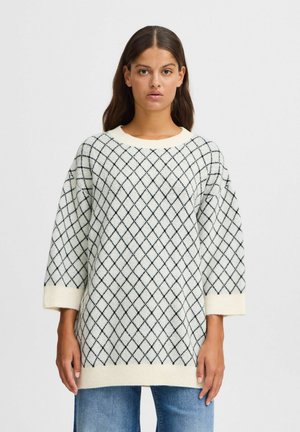Pull créme avec motif en losanges noirs, col rond et manches trois-quarts, doté de bords côtelés aux poignets et à l'ourlet. Design et texture classiques.