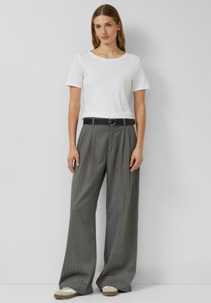 Weißes Kurzarm-T-Shirt kombiniert mit hoch taillierten, grauen, Nadelstreifen-weiten Hosen, die mit einem schwarzen Gürtel mit runder Schnalle befestigt sind.