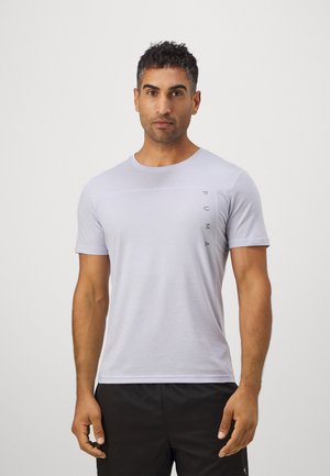 Ljusgrå t-shirt med kort ärm, tillverkad av ett slätt tyg med en subtil textur och en vertikal svart "PUMA"-logotyp på vänster sida.
