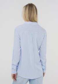 Camicia a maniche lunghe a righe azzurro chiaro e bianca con colletto, dettaglio della piega sul retro e polsini con bottoni, realizzata in un tessuto liscio e leggero.