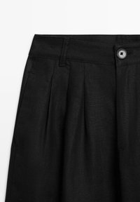 Pantaloni neri vita alta con pieghe, passanti per cintura, tasche laterali e chiusura con bottone in vita.