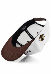 Baseball kapa z belim telesom in rjavim šiltom. Ima vezen žuželko logotip ter črno notranjo oblogo z blagovno znamko.