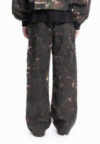 Camouflage cargobukser i grønt, brunt og beige. Løs passform med store sidelommer og slitesterkt stoff. Slitt tekstur fremhever et robust utseende.