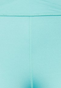Leggings in tessuto blu acquamarina con una consistenza liscia e morbida. Presentano cuciture piatte che scorrono verticalmente per un comfort e una durata maggiori.