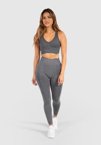 Grijze sportieve crop top en high-waisted leggings, gemaakt van textuurmateriaal, gecombineerd met witte sneakers. Eenvoudig ontwerp, geen patronen of accenten.