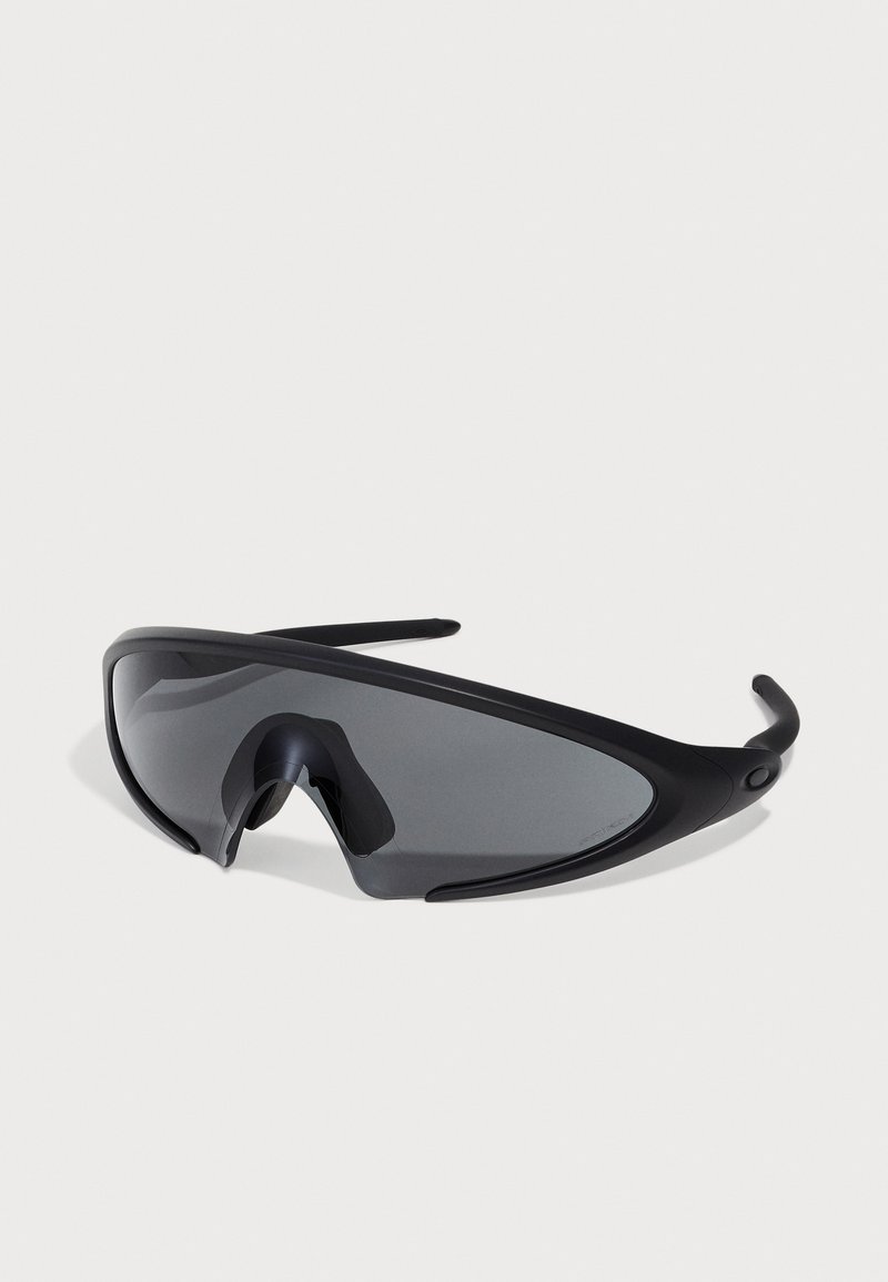Occhiali da sole sportivi neri con lenti a scudo curvo e dettagli in gomma, caratterizzati da un design elegante e aerodinamico e un ponte nasale regolabile.