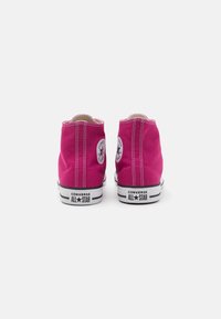 Rózsaszín, magas szárú vászon sportcipők fehér gumi talppal, fekete csíkokkal és Converse All Star logóval mindkét oldalon. Klasszikus fűzős kialakítás.