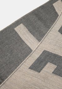 Sciarpa grigia e beige con audaci motivi geometrici, che mostra una combinazione di trame e bordi cuciti, realizzata in un tessuto morbido.