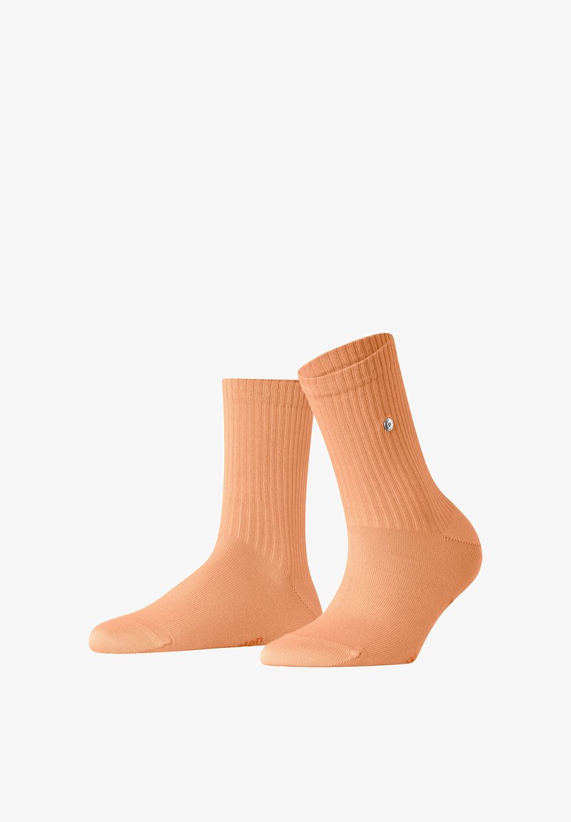 Paire de chaussettes montantes côtelées couleur pêche avec un petit logo rond sur le côté extérieur d'une chaussette, présentées sur un fond blanc.