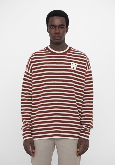 Suéter de punto de rayas marrón y blanco con cuello redondo y logo bordado en forma de "W" en el lado izquierdo del pecho, con mangas holgadas.