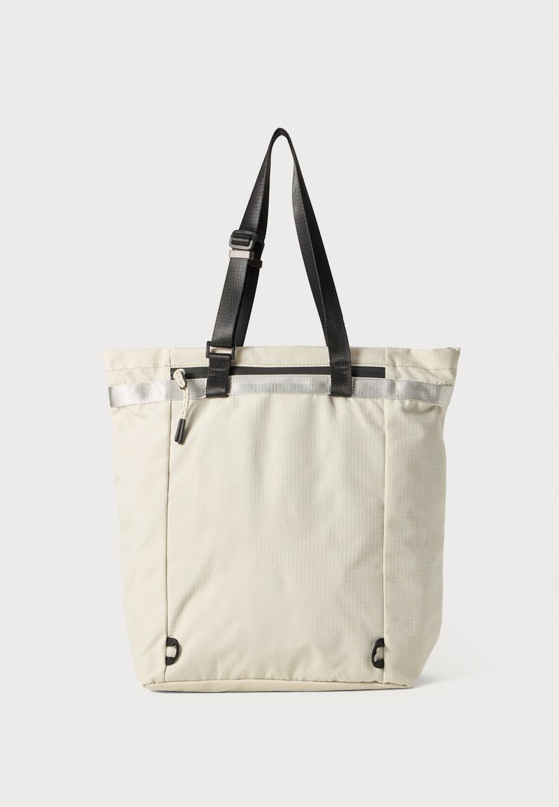 Sac fourre-tout gris clair en tissu durable. Possède des poignées noires et une bande réfléchissante sur le dessus. Comprend des points d'attache sur les côtés.