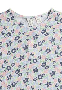 Blomstrede T-shirt med rund halsudskæring. Mønsteret har marineblå, pastelpink og lysegrønne blomster på en lys blå baggrund.