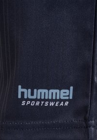 Tissu de sport bleu marine foncé avec logo « hummel SPORTSWEAR » bleu clair imprimé près de l’ourlet cousu