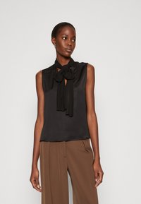 Blusa nera senza maniche in satin con dettaglio a fiocco al collo e apertura a chiave. Tessuto morbido con vestibilità comoda.
