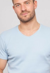 T-shirt bleu clair à col en V à manches courtes, présentant un design ajusté avec une texture lisse et des détails de couture subtils.