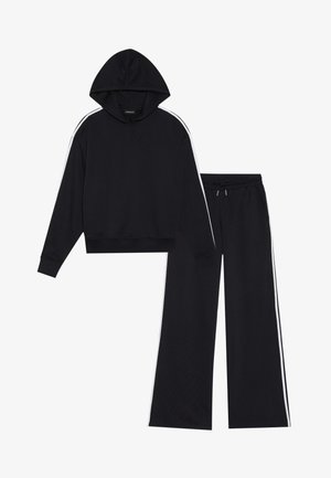 Svart hoodies med huva och vita sidostreck, parat med matchande svarta träningsbyxor med elastisk midja och dragsko.