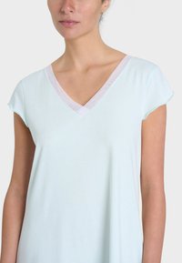 Maglietta a maniche corte azzurro chiaro con scollatura a V e rifinitura bianca trasparente. Tessuto liscio con una vestibilità rilassata e una consistenza morbida.