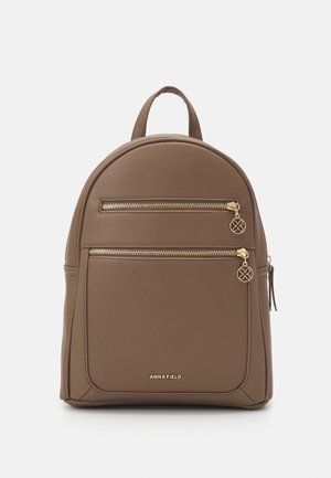 Sac à dos en cuir marron avec deux poches avant zippées dotées de tirettes de fermeture éclair dorées et une poignée de transport supérieure.