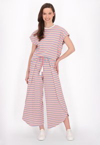 Gestreepte lounge-outfit bestaande uit een losse top en wijde broek. Kleuren zijn onder andere roze, blauw en geel, met een trekkoord in de taille en een tassel.