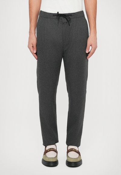 Pantalons de jogging grijs fuselés avec une taille à cordon de serrage, fabriqués dans un matériau doux, dotés de poches latérales et d'un motif texturé subtil.