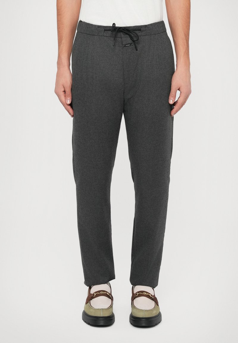 Calças de jogging cinzentas, com corte afunilado e cintura com cordão, feitas de material macio, com bolsos laterais e um padrão texturizado subtil.