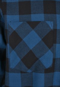 Blå og svart rutete stoff med en lomme, med et geometrisk mønster og en glatt tekstur. Designet er jevnt med klare, sterke linjer.