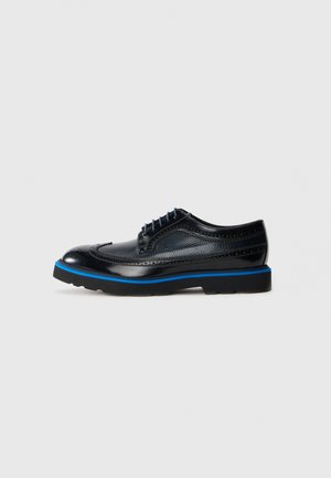 Black leather brogue shoe with blue sole stripe and black laces on light gray background, side view.