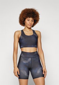 Sports-bh og shorts-sett i svart med et teksturert bølgemønster i blått og sølv. Inni passform med bred midjebånd og dyp utringning.