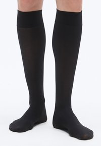 Sorte knæstrømper i glat, elastisk materiale med ensfarvet design uden mønstre eller detaljer. Har en blød kant øverst.