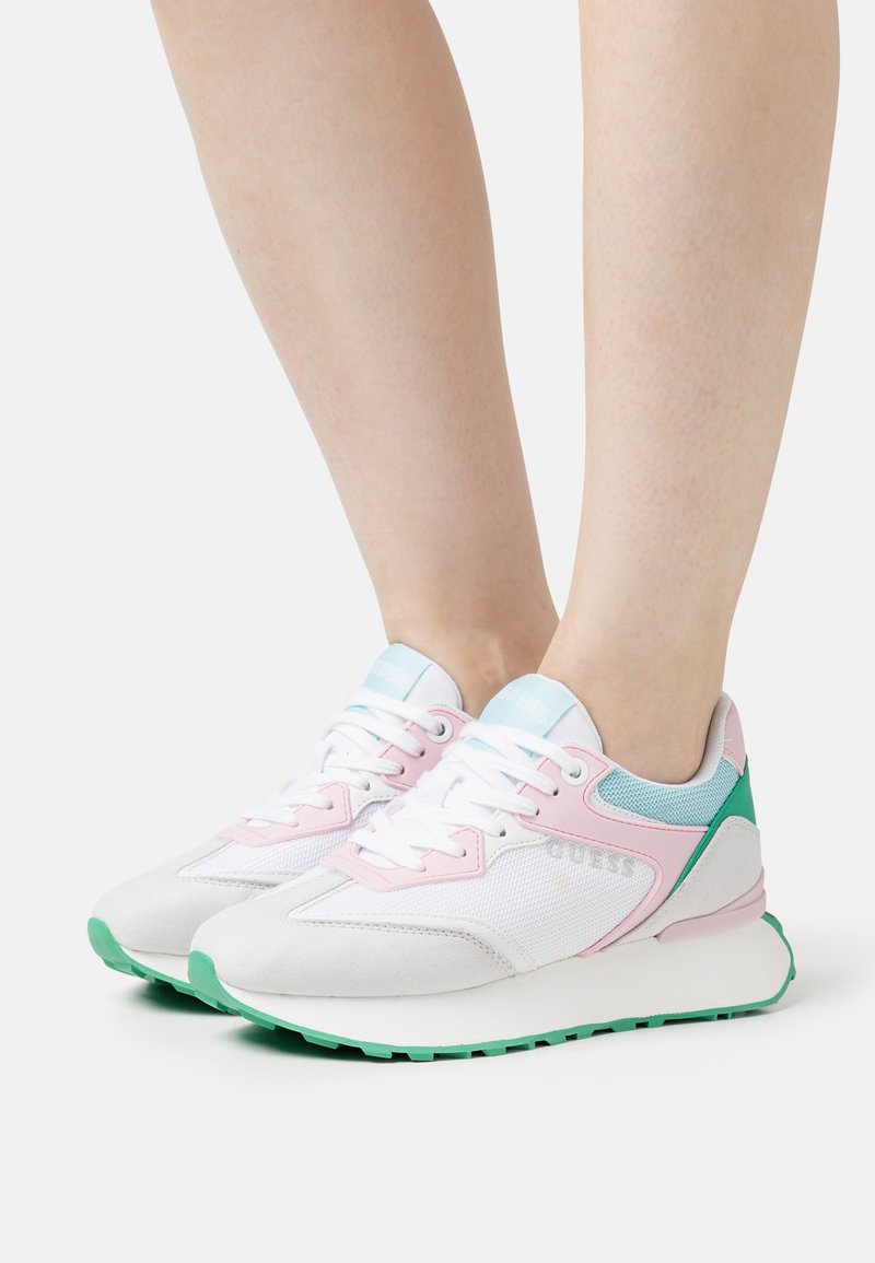 White sneakers with pink accents and green soles, featuring a mesh design, lace-up closure, and minimal branding. Rubber outsole.