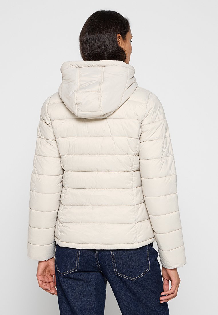 Giacca puffer beige chiaro con cappuccio, caratterizzata da sezioni trapuntate orizzontali e una superficie liscia. Messa in risalto da un design semplice e pulito.