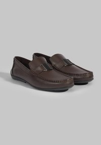 Bruine leren loafers met een ronde neus, decoratieve stiksels en een metalen accent op de wreef; textuur oppervlak, flexibele rubberen zool.