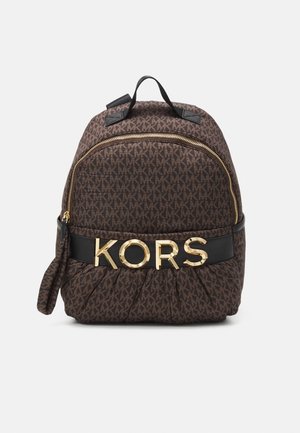 Mochila marrón con estampado, cremallera dorada y grandes letras doradas "KORS" en una correa negra en la parte delantera, con asa superior.