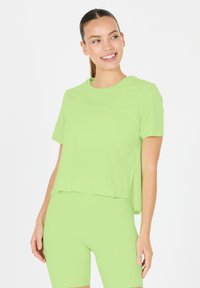 Vaaleanvihreä, lyhythihaisesta t-paidasta, jossa on rento leikkaus ja sivuhalkiot, valmistettu sileästä, joustavasta kankaasta, yhdistettynä samansävyisiin shortseihin.