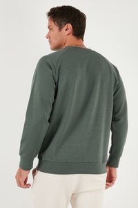 Felpa verde scuro con polsini e orlo a costine, caratterizzata da un collo rotondo e un tessuto semplice e strutturato. Nessun motivo decorativo visibile.