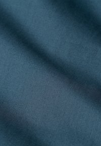 Tessuto morbido e strutturato in un profondo colore teal, caratterizzato da una lucentezza sottile e una superficie liscia, ideale per varie applicazioni tessili.