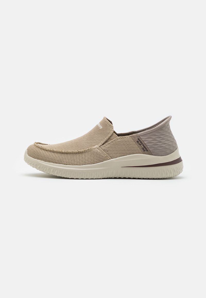 Beige kengät ilman nauhoja, joissa on teksturoitu verkko-yläosa, pyöristetty kärki ja pehmustettu pohja. Tummemmasta beigestä yksityiskohdat kantapaikassa.