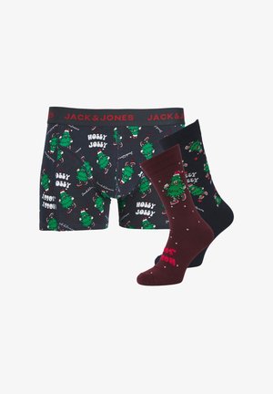 Die Boxershorts haben ein dunkles Design mit grünen Weihnachtsbaum-Mustern und dem Text "HOLLY JOLLY". Die Socken umfassen ein bordeauxfarbenes Paar mit weißen Punkten.