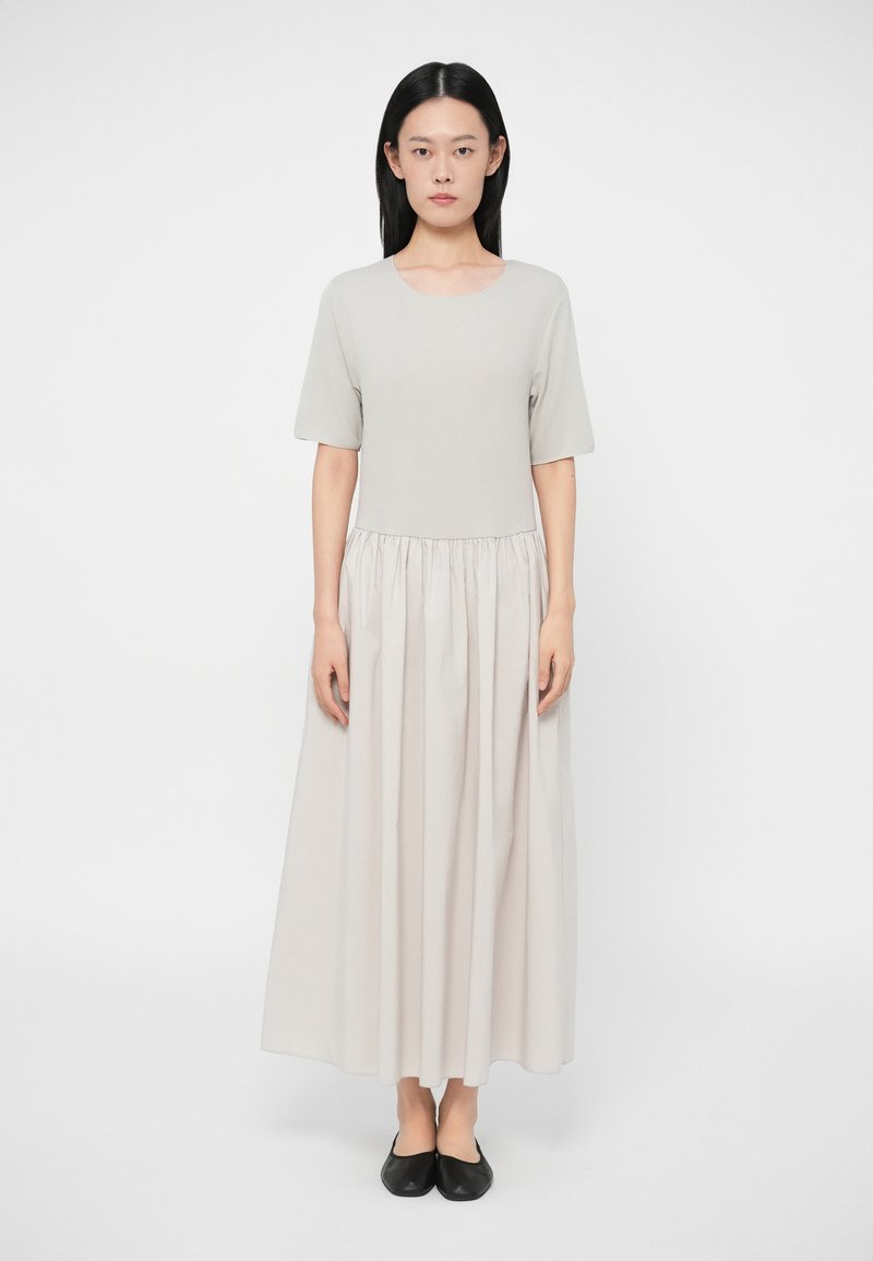 Pilka, iki kelių ilgio suknelė su prigludusia liemene ir susiraukšlėta juosta, pereinanti į pilną, ilgą sijoną. Dėvima su juodais butais. Lygus paviršius.